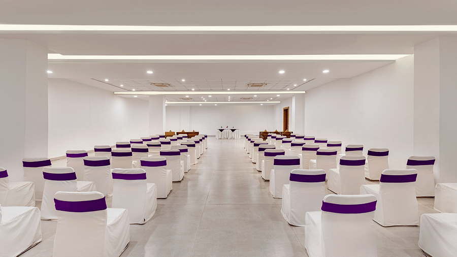 Empty conference room with rows of chairs draped with white tablecloths - Via Lakhela Resort & Spa