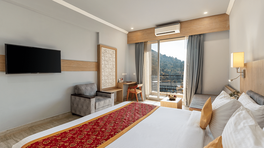 A hotel room with a bed, TV, seating, desk, and a balcony with a view - Via Lakhela Resort & Spa, Kumbhalgarh