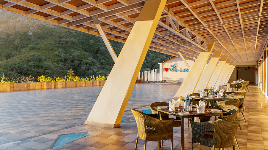 Outdoor dining area with tables, chairs, and a unique sloped roof - Via Lakhela Resort & Spa