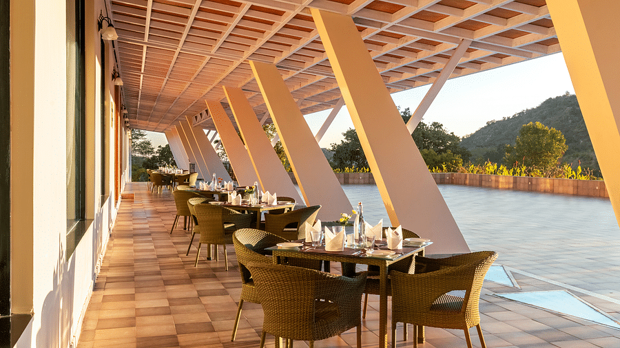 Outdoor dining area with sloped roof, tables, chairs, and a scenic view - Via Lakhela Resort & Spa