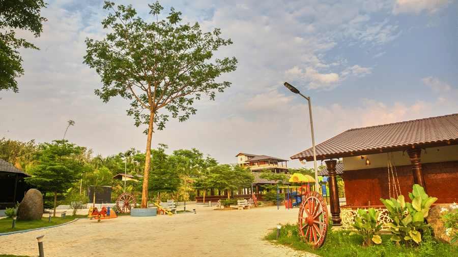 A paved outdoor area with a decorative street lamp and green landscaping, leading towards a modern building under a bright sky. - Vintage Trails by Ilara