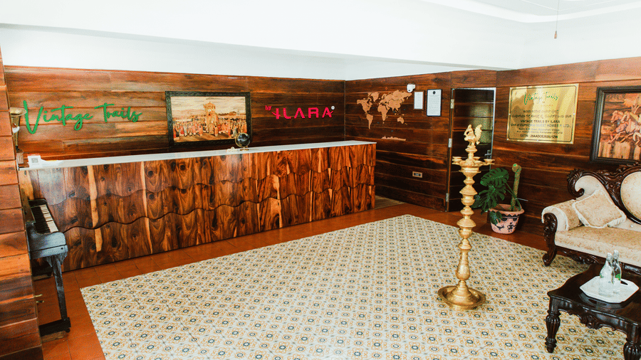 A resort reception lobby area featuring tiled flooring, a long wooden front desk, and a decorative brass floor lamp | Vintage Trails By Ilara