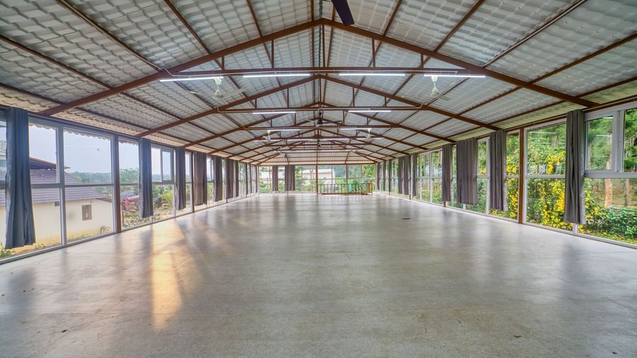  A large, empty hall with a high, exposed truss ceiling and a light-coloured concrete floor, viewed from a slightly different angle, showing more of the expansive space. - Vintage Trails by Ilara