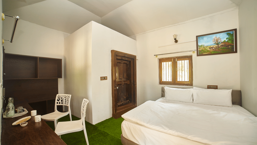 The interior of a white, modern, capsule-style accommodation unit with a large circular bed, a round green rug, and a small built-in desk or shelf. - Vintage Trails by Ilara