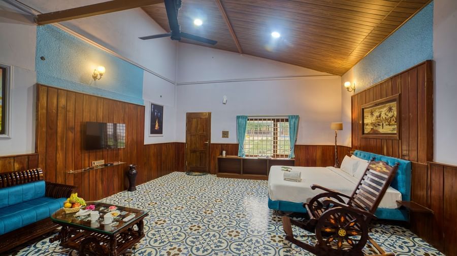 The interior of a room with a patterned floor, and wooden ceilings, featuring a sofa, a rocking chair, and a decorative coffee table. - Vintage Trails by Ilara