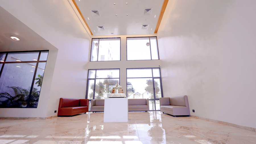 The grand, sunlit double-height lobby at Vinti Resort, Ambaji features chic minimalist seating and expansive glass windows.