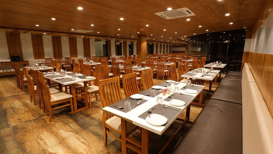 Warmly lit interiors of the Blue Coriander Restaurant with wooden tables and chairs in a cosy atmosphere - Vishal Lords Inn Gir Forest