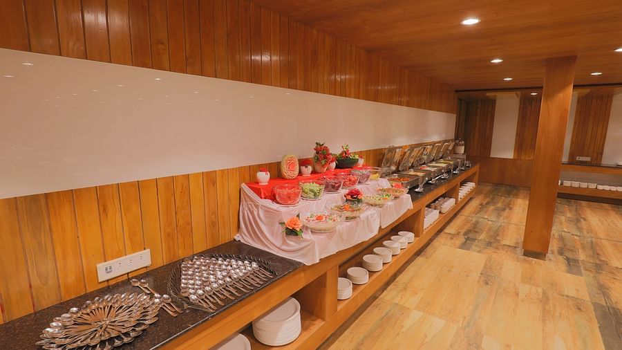A buffet area with a variety of dishes displayed on a long counter - Vishal Lords Inn Gir Forest