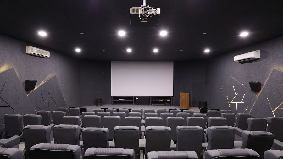 A private cinema room with rows of plush seating facing a large projection screen - Vishal Lords Inn Gir Forest