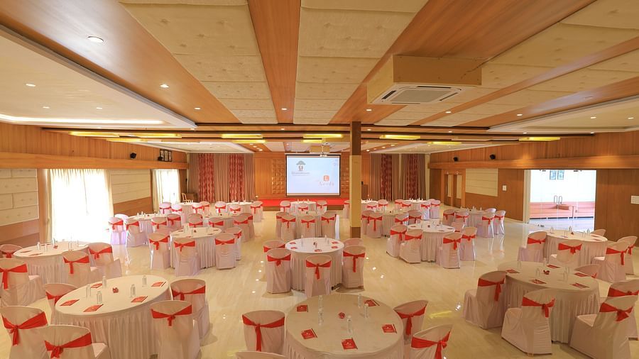 An expansive banquet hall with round tables draped in white and pink table cloth, ready for an event - Vishal Lords Inn Gir Forest