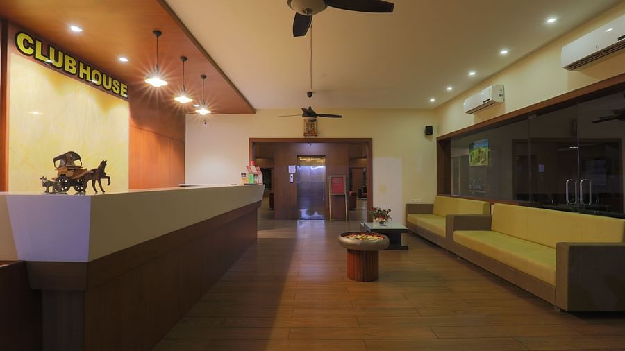 A spacious lobby area with sofas, a ceiling fan, and a view towards the exterior greenery from the wide window - Vishal Lords Inn Gir Forest