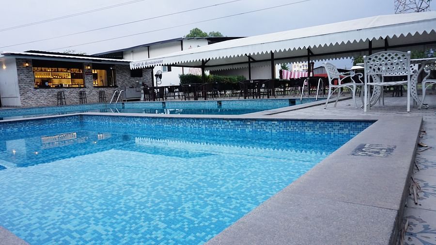 Pool and dining area with tents at dusk. | Vistar Resort, Bengaluru