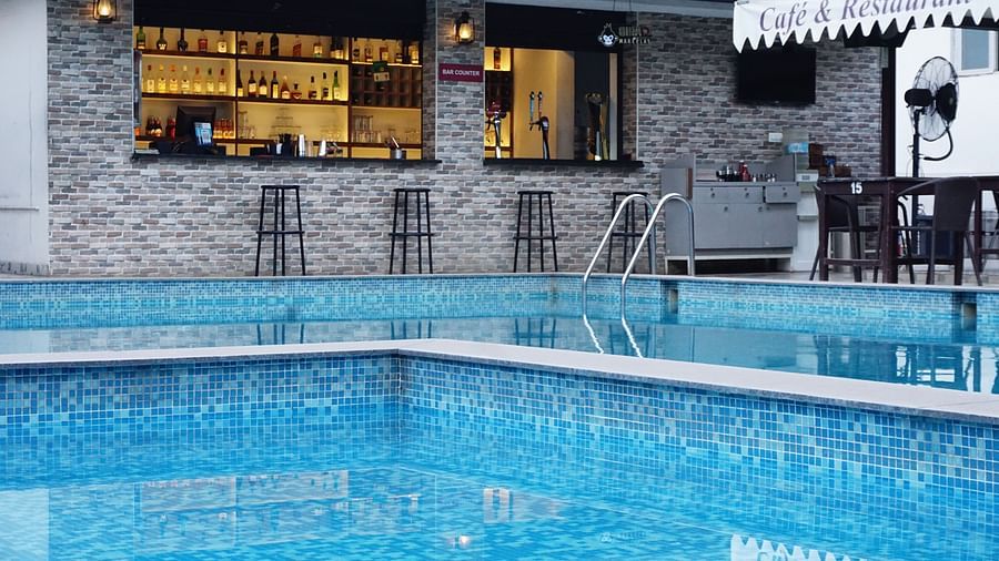 Bar next to pool under evening sky. | Vistar Resort, Bengaluru