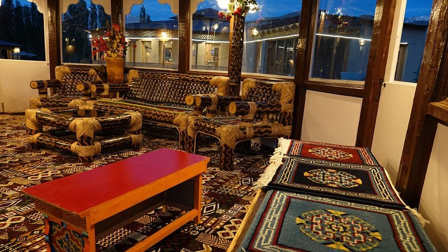 An indoor seating area at night with wooden furniture and decorative carpets is illuminated by warm lighting at White Sands Resort, Ladakh.