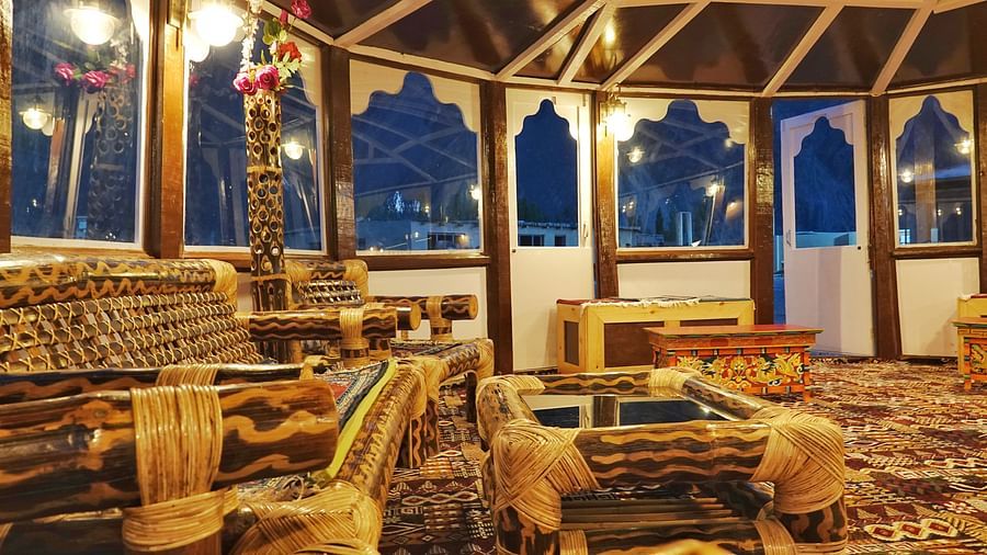 A cosy indoor space with intricate wooden architecture and comfortable seating arrangements is bathed in soft light at White Sands Resort, Ladakh.