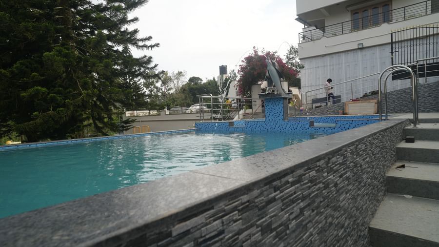 Full view of the swimming pool along with a series of staircase leading to the brim of the pool at WOW Naturefull Resorts.
