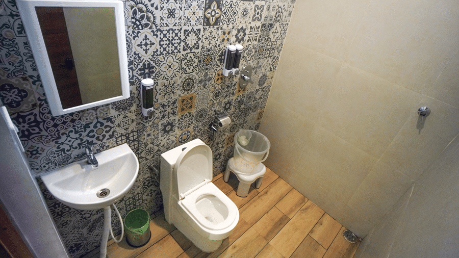 A room at WOW Naturefull Resorts, Yercaud, with a toilet seat, a sink, a mirror, and a shower head.