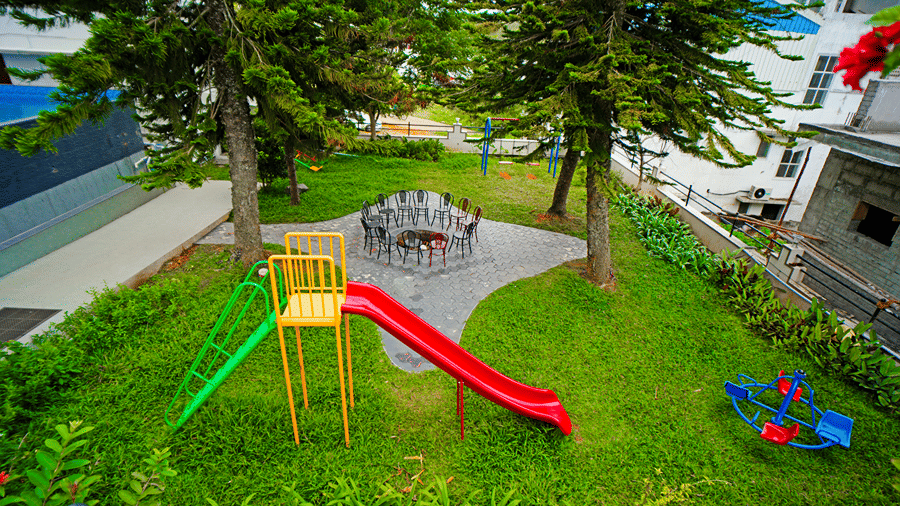 An overhead view of a playground nestled in a grassy area with trees, featuring a playground slide.