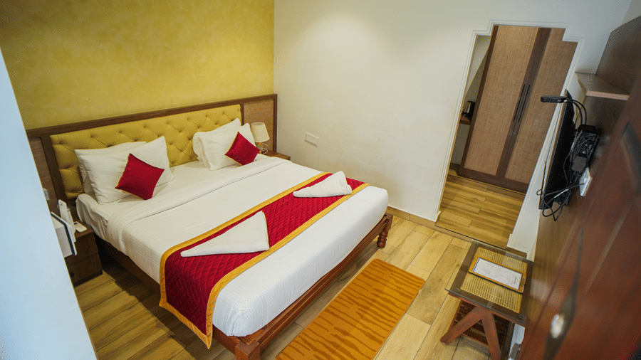 A room at WOW Naturefull Resorts, Yercaud, with a large bed, spreads, pillows, a table, and a TV.