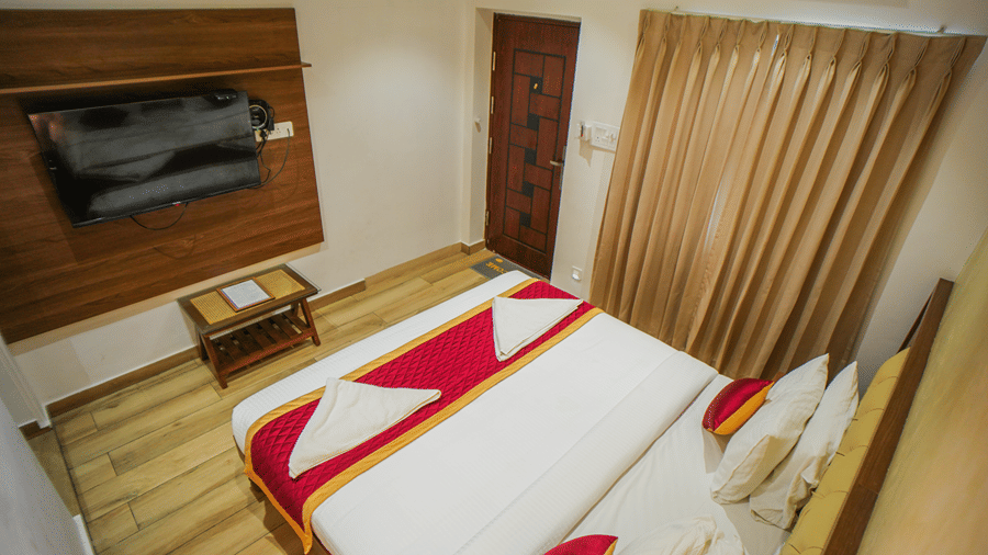 A room at WOW Naturefull Resorts, Yercaud, with a large bed, spreads, pillows, a table, and a TV.