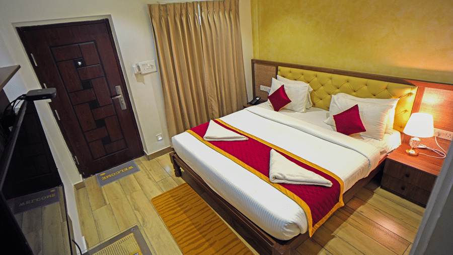 A room at WOW Naturefull Resorts, Yercaud, with a large bed, spreads, pillows, a table, and a TV.