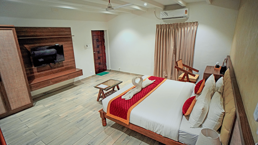 A room at WOW Naturefull Resorts, Yercaud, with a large bed, spreads, pillows, an air-conditioner, a table, and a TV.