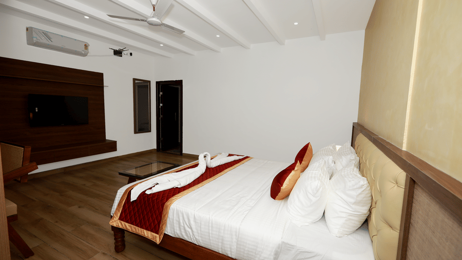 Side view of the double bed at the Nature Luxury Room with towel swans kept on the bed runner at WOW Naturefull Resorts, Yercaud.