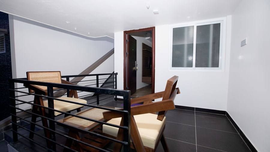 The exterior of the Nature Luxury Room featuring an outdoor seating area with 2 cushioned arm chairs at WOW Naturefull Resorts, Yercaud.