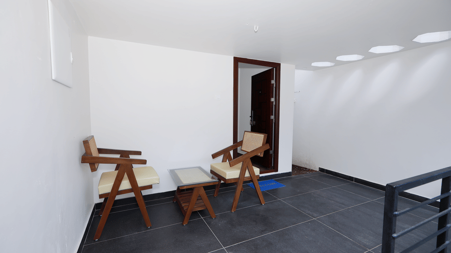 A sleek outside seating area with dark grey flooring, featuring 2 cushioned arm chairs in the Terrace Cottage at WOW Naturefull Resorts, Yercaud.