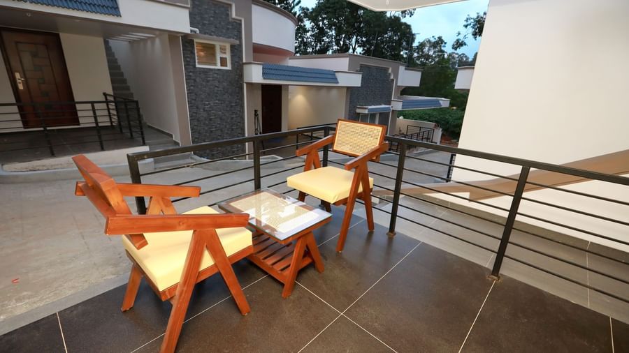 Close up of the 2 arm chairs kept in the outdoor seating area of Nature Luxury Room overlooking the pathway beside it connecting other lodges at WOW Naturefull Resorts, Yercaud.
