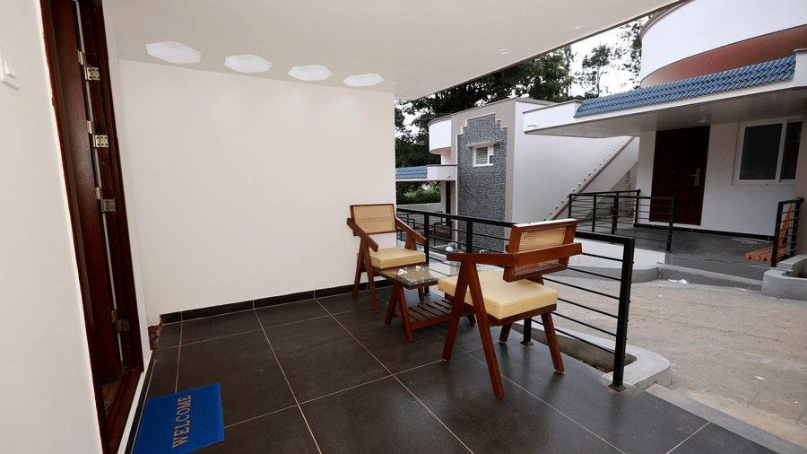 The entrance of the Terrace Cottage with an outdoor seating area featuring 2 arm chairs at WOW Naturefull Resorts, Yercaud.