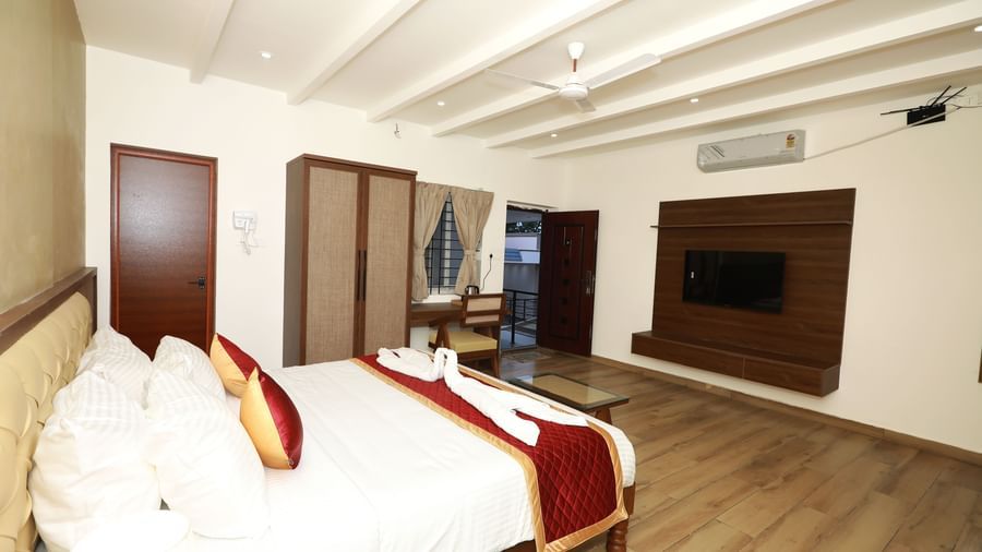Side view of the Nature Luxury Room featuring a wardrobe and a wall-mounted split AC, along with a double bed at WOW Naturefull Resorts, Yercaud.