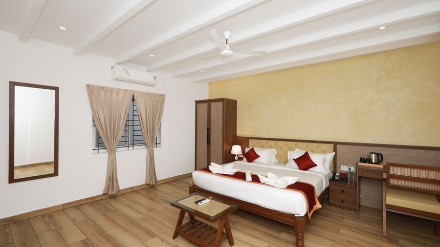 A brightly-lit interior of the Terrace Cottage featuring a double bed along with a wall-mounted mirror at WOW Naturefull Resorts, Yercaud.
