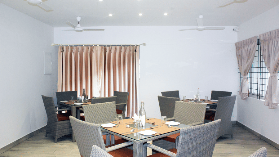 A wide-angle shot of the Spice and Slice Restaurant with 3 dining tables arranged in the dining area at WOW Naturefull Resorts, Yercaud.