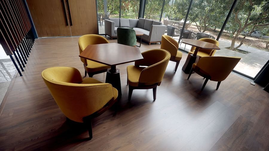 Elegant group seating with round wooden tables and plush yellow chairs in a sunlit room at Wyndham Garden.