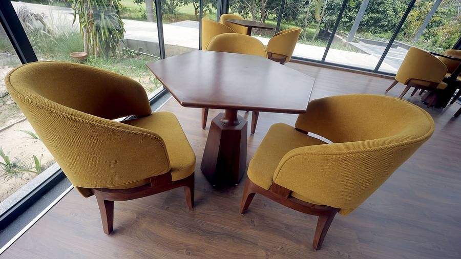 Cosy wooden table setting with mustard yellow armchairs beside large windows at Wyndham Garden.