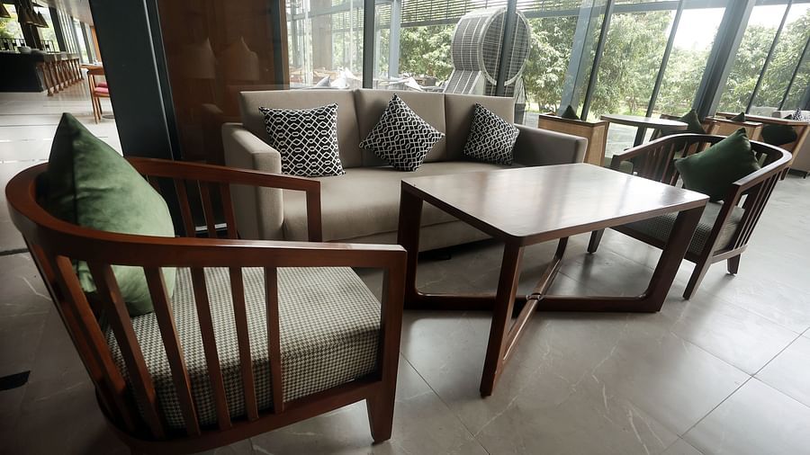 Bar area featuring a wooden sofa set with neutral-toned cushions near expansive windows at Wyndham Garden.