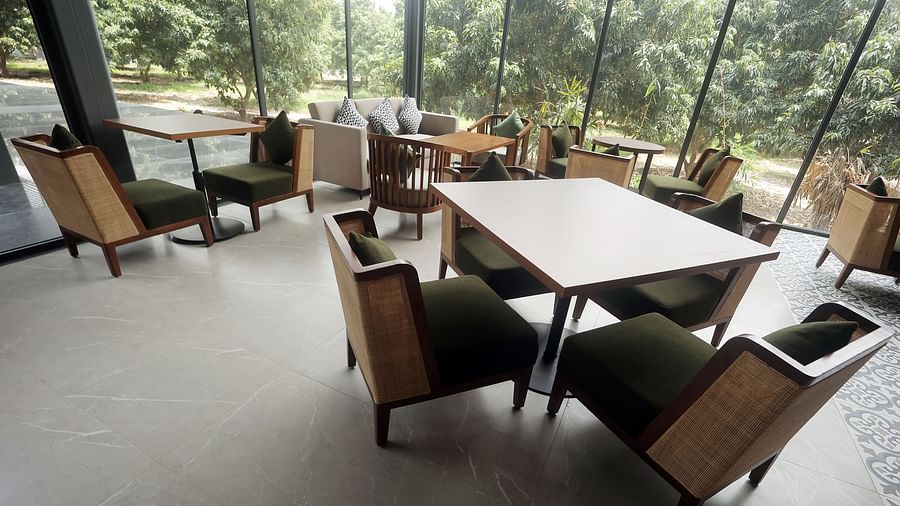 Indoor seating with wooden chairs and orchard views through tall glass panels at Wyndham Garden.