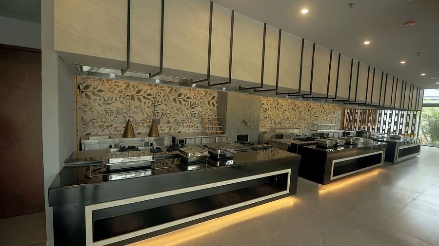 Buffet counter with modern chafing dishes, stone wall backdrop, and warm under-counter lighting at Wyndham Garden.