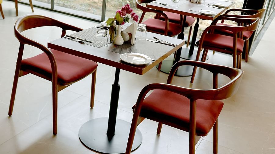 Modern dining setup with red-cushioned wooden chairs and neatly arranged tableware near glass walls at Wyndham Garden.