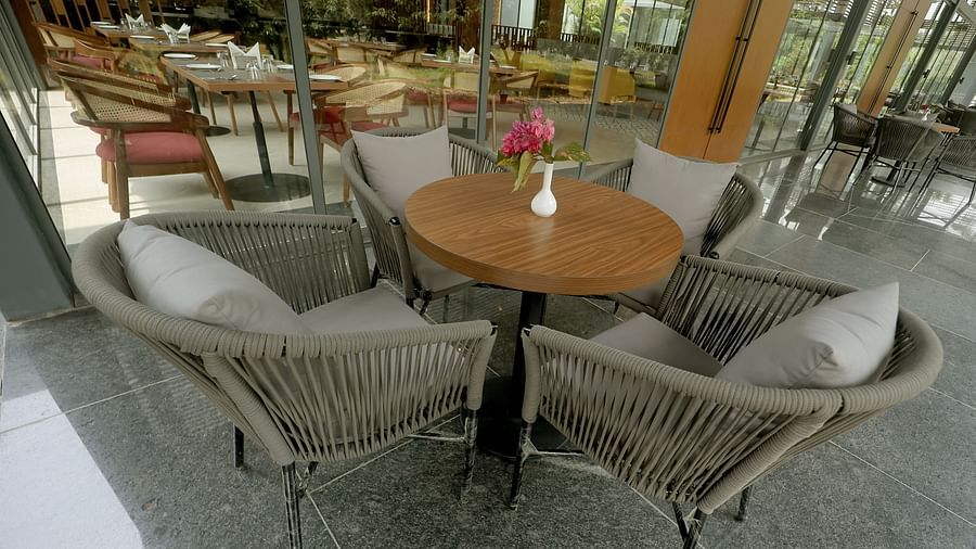 Outdoor-style seating with grey rope chairs and a wooden table, surrounded by natural views at Wyndham Garden.