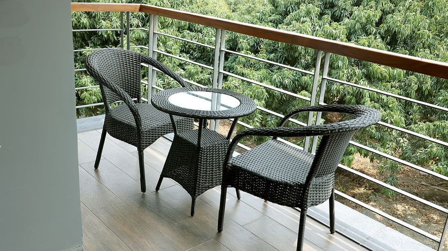 Cosy balcony setup with a round table and two wicker chairs overlooking lush foliage at Wyndham Garden.