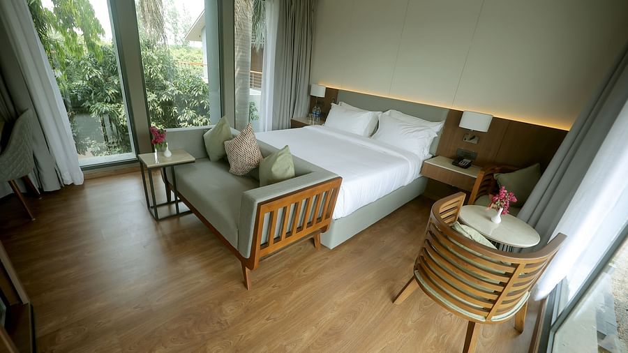 King size bed with green garden view through large glass doors and a cosy seating arrangement at Wyndham Garden.
