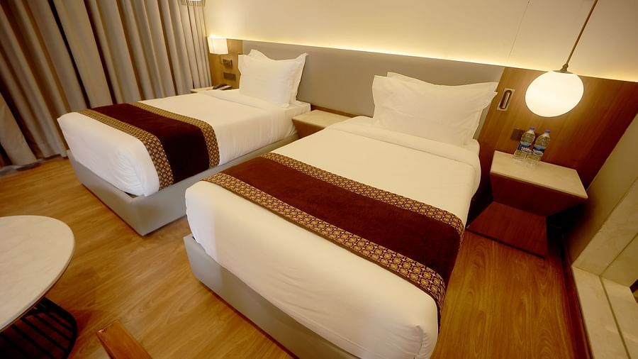 Twin bedroom with wooden flooring, soft lighting, and a bedside table setup at Wyndham Garden.