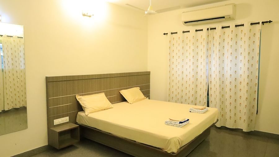 A well-lit bedroom with a comfortable bed with a head board and curtains.
