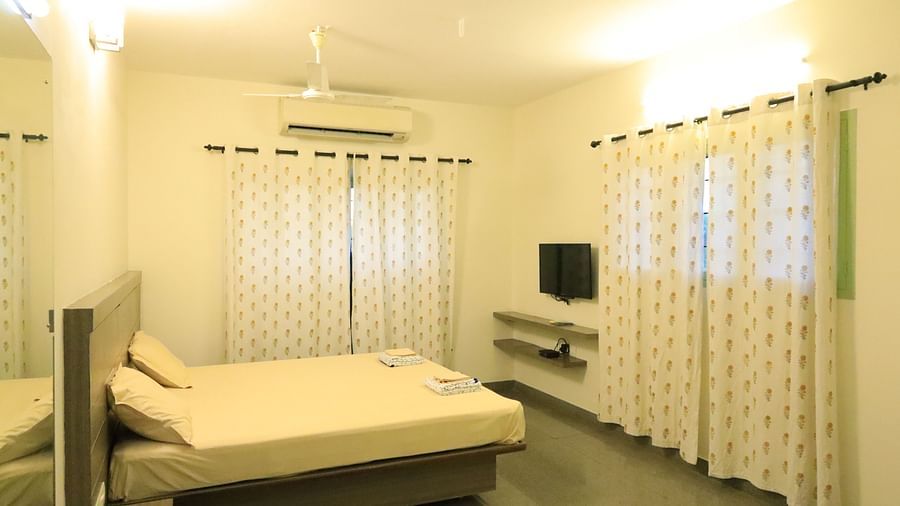 A room at Wyt Hotels Transit Nest, Madurai featuring a double bed, curtains covering windows, and a flat TV screen.