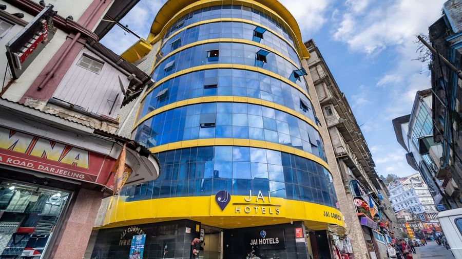 The bright yellow and blue glass exterior of the Yashshree Jai Hotel & Banquet, Darjeeling building.