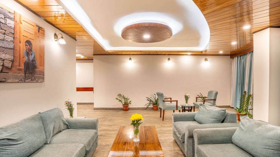 A stylish and modern hotel lobby with blue-grey sofas at the Yashshree Jai Hotel & Banquet, Darjeeling.