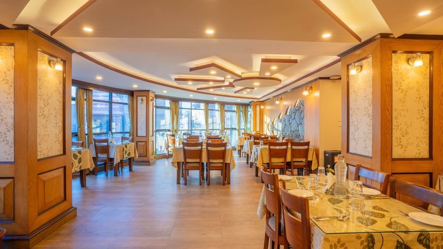 A bright and modern restaurant with elegant tables and chairs at the Yashshree Jai Hotel & Banquet, Darjeeling.