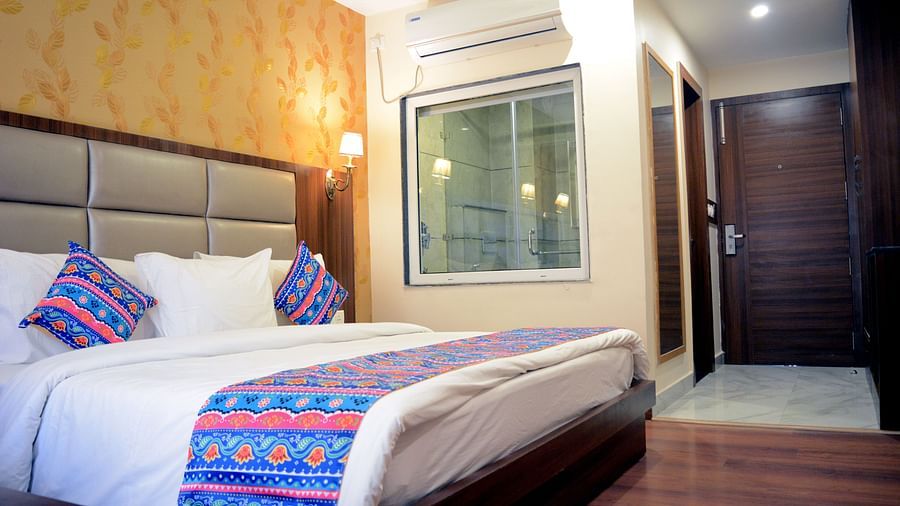 a close up image of the superior room featuring a plush double bed with soft comforter with a translucent glass partition - ZENQ SIGNATURE INN, MCLEODGANJ
